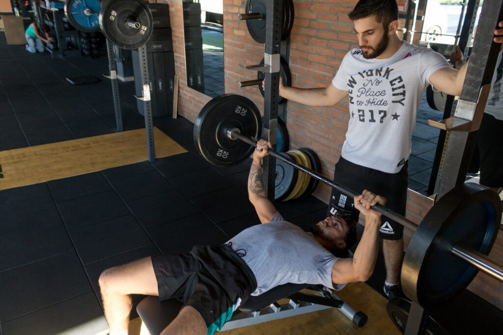 Man with heavy weights on bench press with a spotter